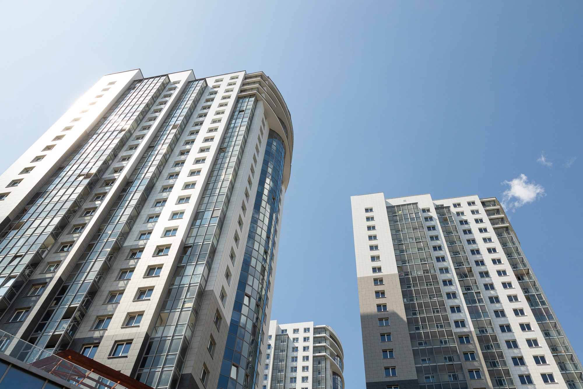 ground diagonal view of high modern luxury tiled apartment building on blue sky background.
