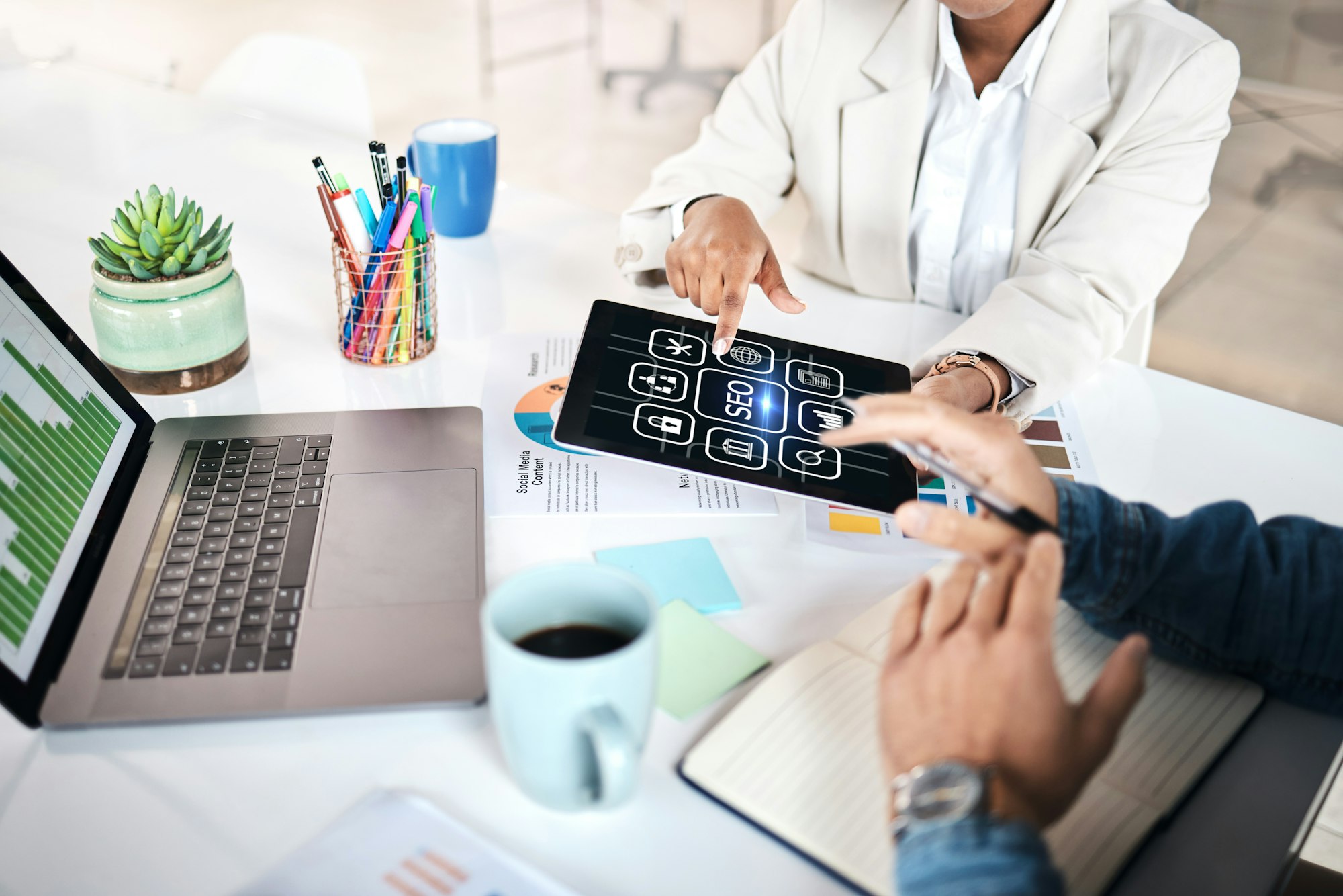 Business people, hands and tablet with icons for marketing, analytics or SEO at the office. Group w