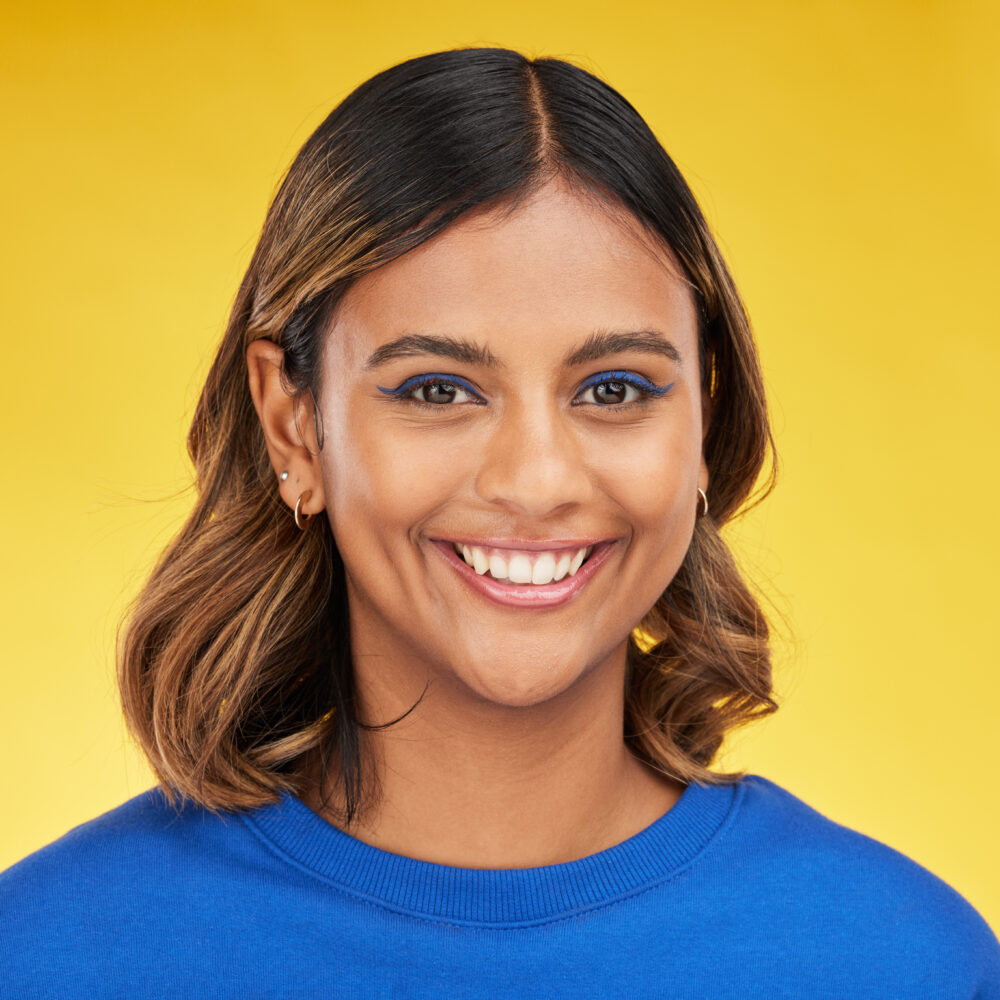 Portrait, smile and makeup with a woman on a yellow background in studio for fashion or cosmetics.